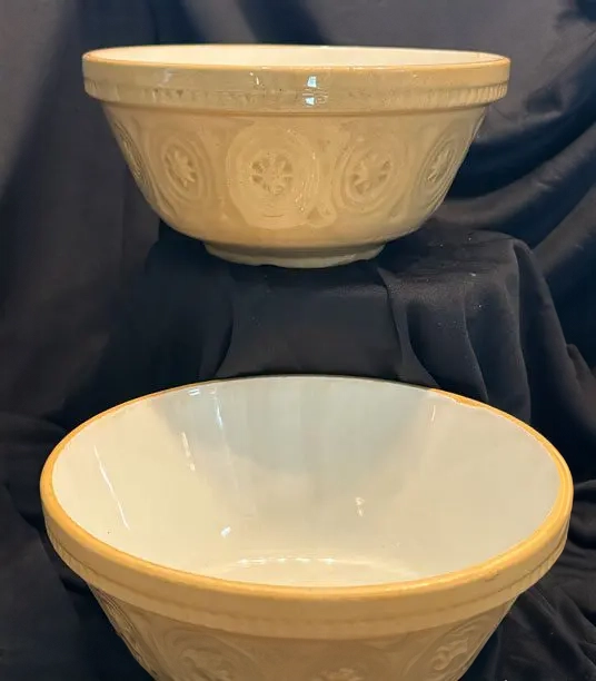 Two bowls are sitting on a table and one is white.