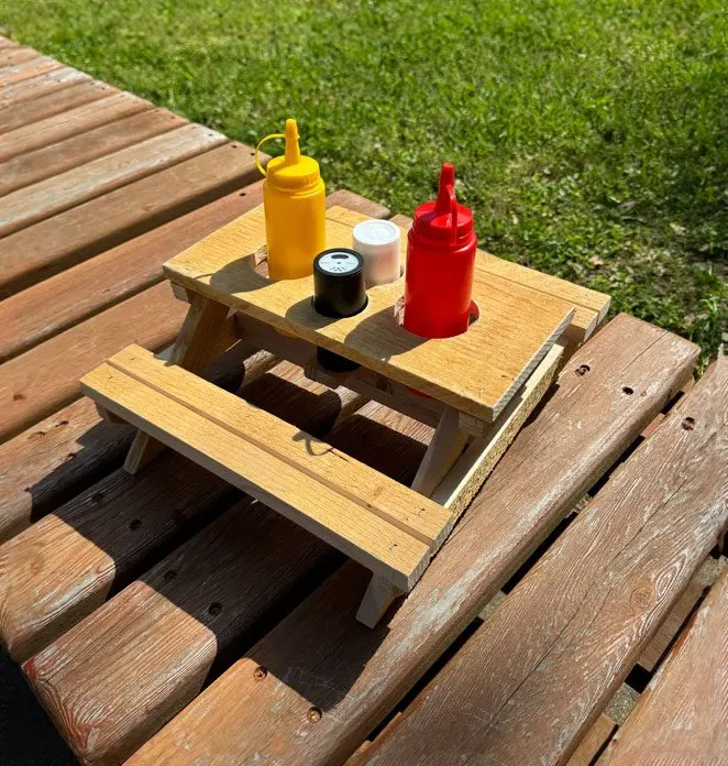 A picnic table with condiments on top of it.