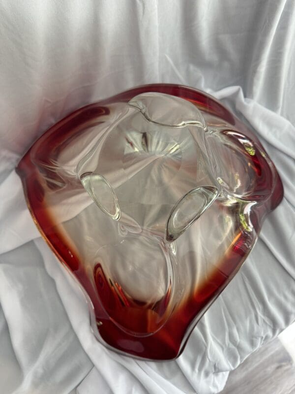 A red and white glass bowl sitting on top of a table.