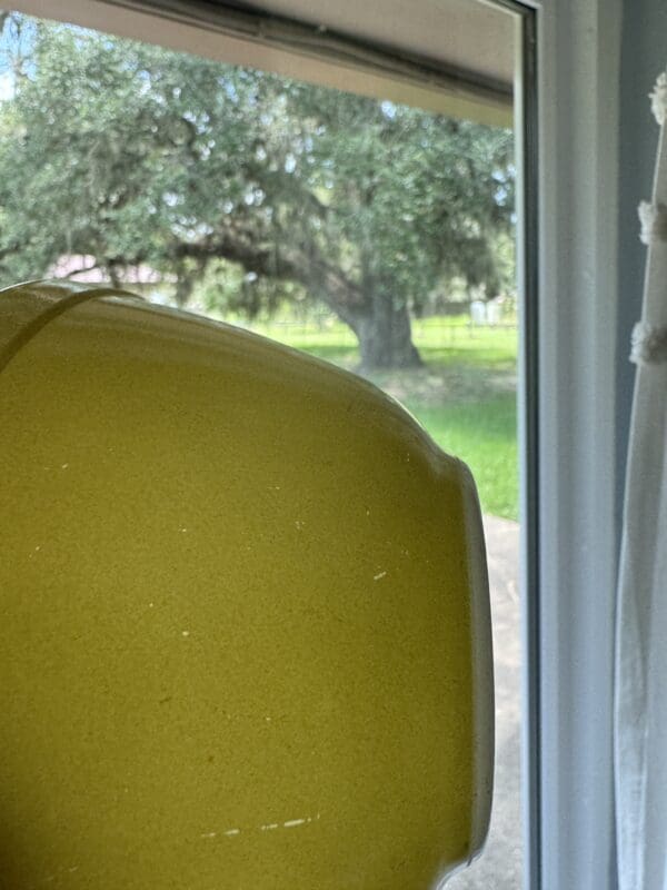 A yellow chair in front of a window.