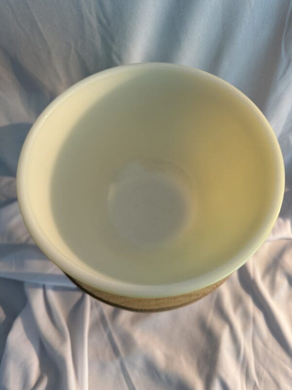 A white bowl sitting on top of a bed.