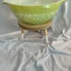 A green bowl sitting on top of a wooden stand.