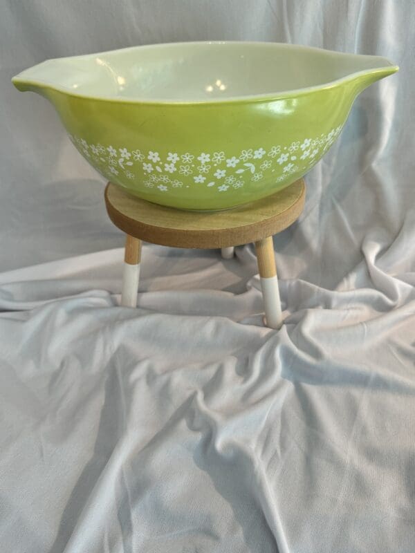 A green bowl sitting on top of a wooden stand.