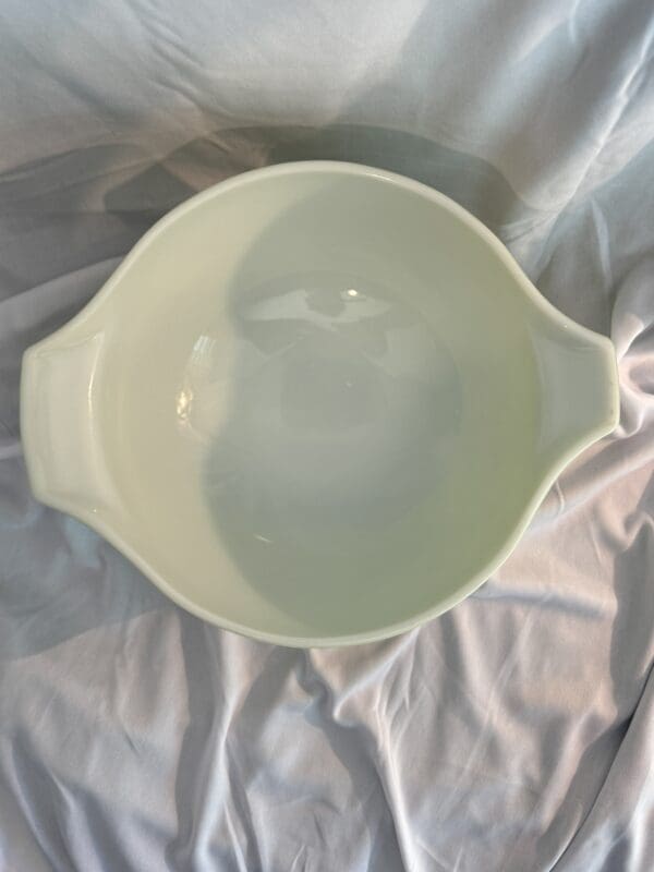 A white bowl sitting on top of a bed.