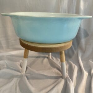 A bowl on a stand is sitting on the floor.