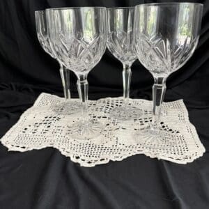A set of four wine glasses on top of a doily.