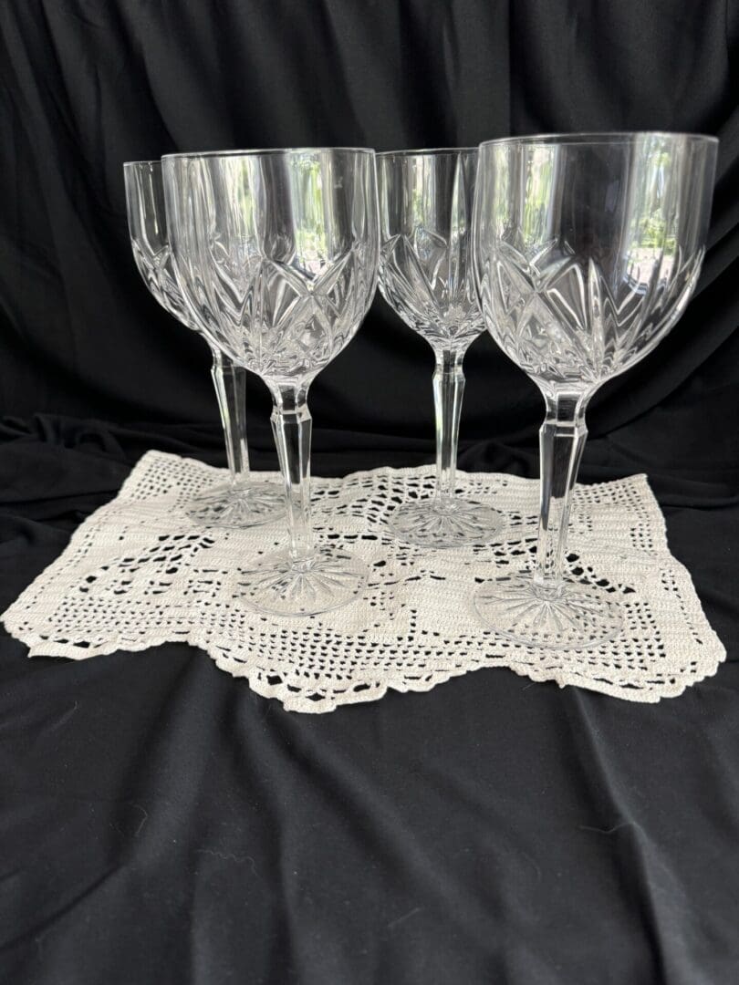 A set of four wine glasses on top of a doily.