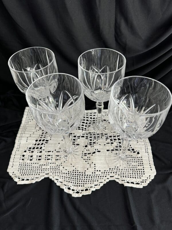 A set of four glasses on a doily.