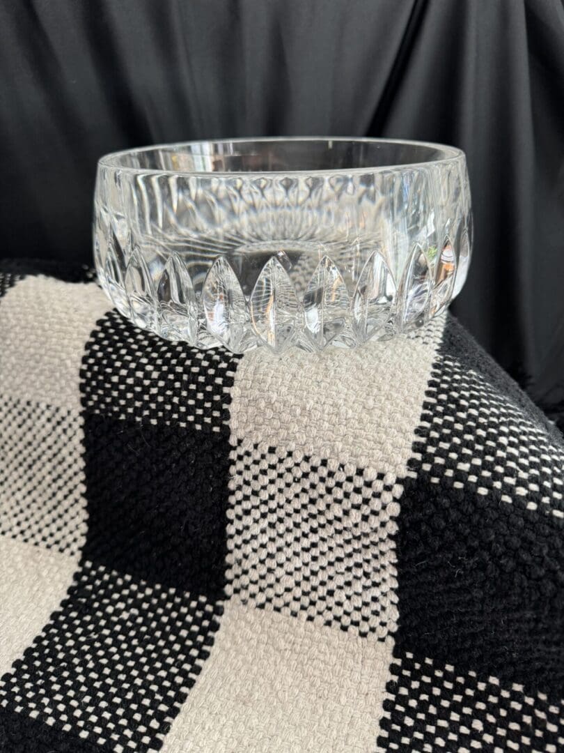 A glass bowl sitting on top of a black and white checkered blanket.