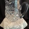 A glass pitcher sitting on top of a crocheted doily.