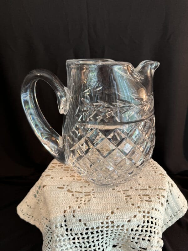 A glass pitcher sitting on top of a white pedestal.