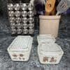 A counter with two containers and utensils in it.