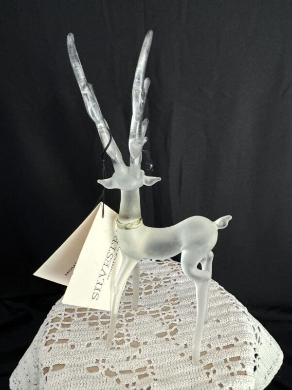 A glass deer with a white background and some paper