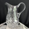 A clear glass pitcher sitting on top of a table.