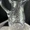 A clear glass pitcher sitting on top of a table.