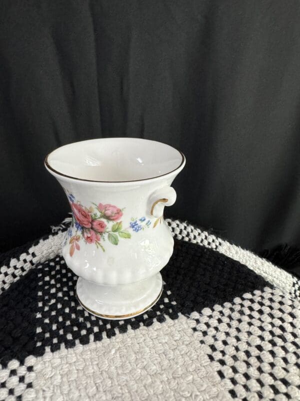 A white vase with flowers on top of a black and white table.