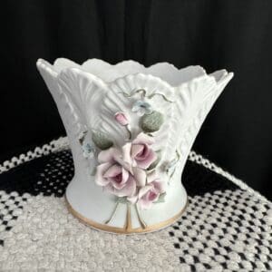 A white vase with pink flowers on top of a table.