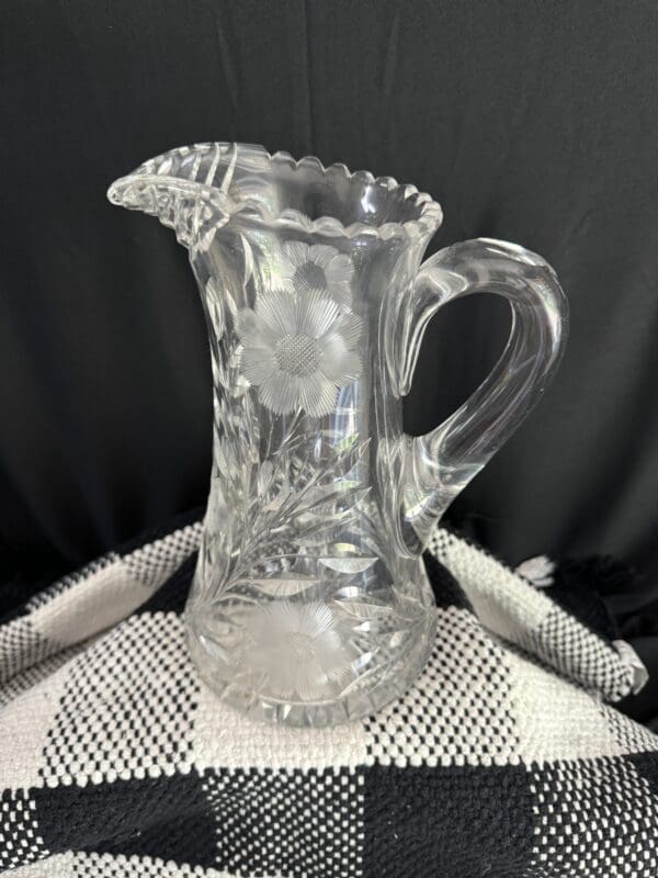 A clear glass pitcher sitting on top of a table.