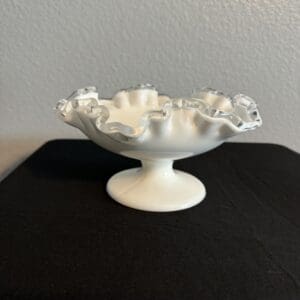 White ruffled glass bowl on a black surface.