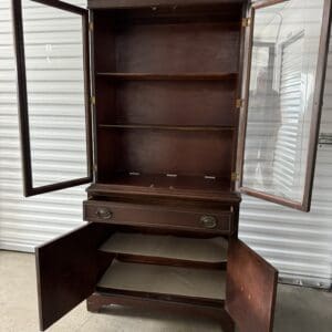 Wooden cabinet with glass doors opened.