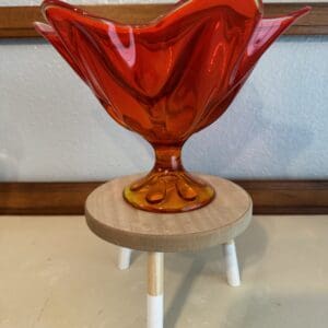 Red glass bowl on a wooden stand.