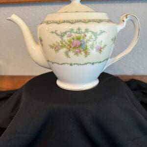 Decorative floral teapot on black fabric.
