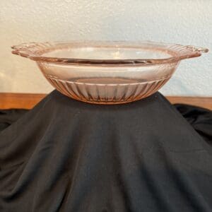 Pink glass pie dish on black fabric.